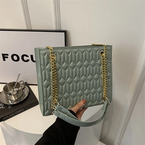Sage green quilted lattice crossbody bag with gold chain strap in a lifestyle setting