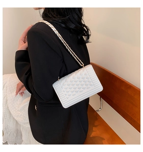 Detail view of white chain strap square bag on model showing luxury textured finish