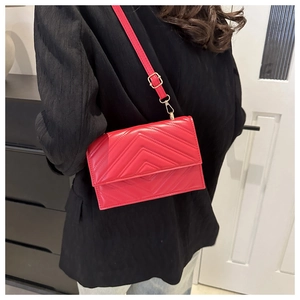 Détail du sac bandoulière rouge matelassé avec d'élégantes boucles en métal doré brillant