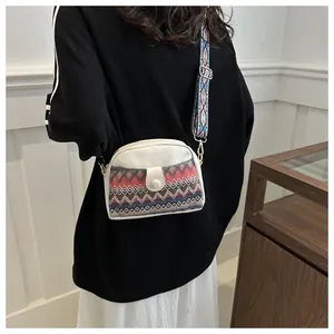 Ethnic crossbody bag with colorful woven strap and embroidered wave pattern details