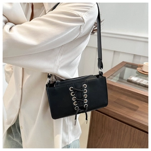 Détail du sac sous l'aisselle en cuir verni noir avec lacets et œillets argentés