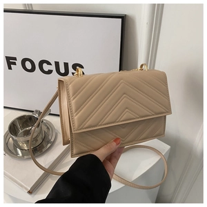 Détail du sac bandoulière matelassé beige avec motif en V et ferrures dorées