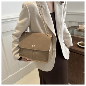 Close-up of khaki chain bag featuring shiny leather texture and gold twist lock