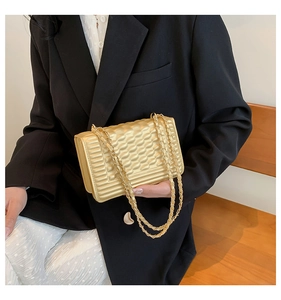 Detailed close-up of metallic gold quilted chain bag with elegant textured finish