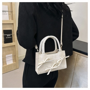Détail du petit sac blanc avec nœuds décoratifs et bandoulière pour un style chic