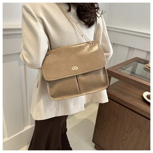Close-up of light khaki vintage leather crossbody bag with gold chain and turn-lock
