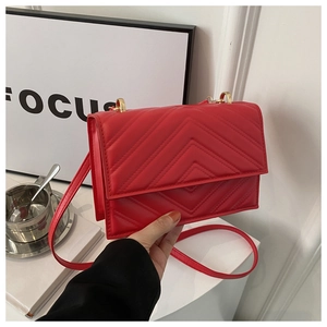 Détail du sac à bandoulière rouge avec matelassage en V et anneau en métal doré