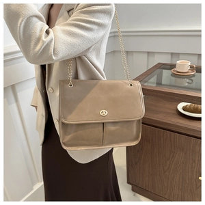 Detail of beige leather crossbody bag with gold chain strap and metal rotary lock closure