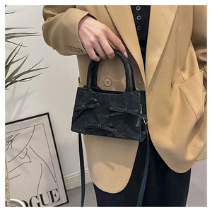 Détail du sac à main noir à nœuds, texture mate, porté avec un blazer kaki élégant