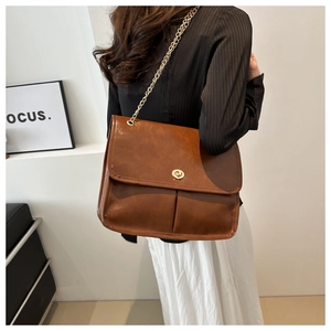Detail of vintage brown leather shoulder bag with gold chain strap and turn-lock closure