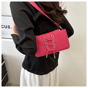 Détail du sac à bandoulière en cuir verni rose rouge avec laçage chic à œillets argent