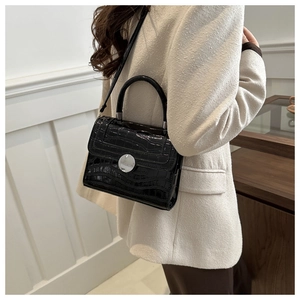Close-up of black crocodile pattern leather bag with silver round lock and metal hardware