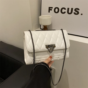 White quilted flap bag with dark metal chain strap shown in a modern lifestyle setting