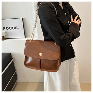 Detail of vintage brown oil wax leather bag with golden chain strap and turn-lock