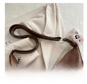 Dettaglio borsa tote marrone in pelle con texture PU liscia e ciondolo orsetto di peluche