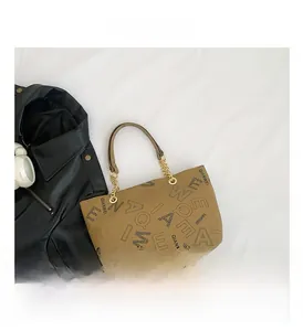 Detailed top view of beige tote bag with letter prints and gold chain leather straps