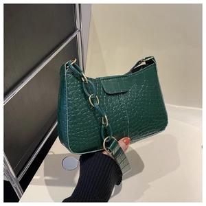 Dettaglio della borsa sottobraccio verde scuro con trama a coccodrillo e catena dorata