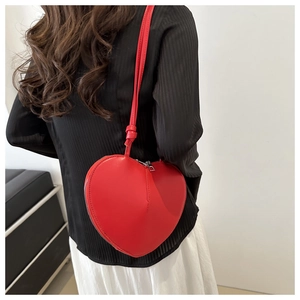 Détail d'un mannequin portant un sac à bandoulière rouge brillant en forme de cœur