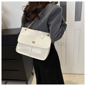 Detailed back view of a white glossy flap shoulder bag with gold chain strap on a model