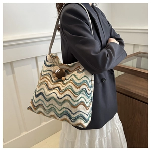Detail of knit tote bag with multicolor zigzag pattern and cute monster charm accessory