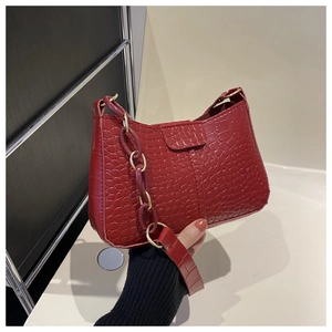 Dettaglio borsa baguette rossa stampa coccodrillo con catena in metallo dorato