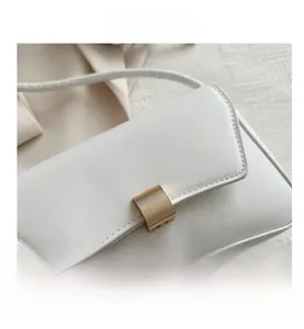 Close-up of white leather handbag with golden rectangular buckle and precise stitching