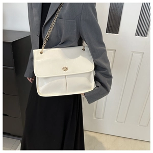 Detail of cream white glossy leather shoulder bag featuring a gold twist lock and chain strap