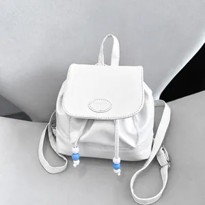 Detalle de mochila de cuero PU blanco con cierre de solapa, cordón y logotipo de moda grabado