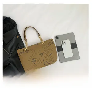 Flat lay of brown PU tote bag with letter patterns, gold chain strap, and tablet for scale