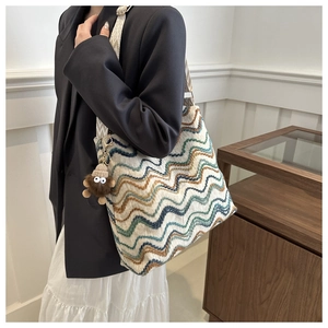 Close-up of ethnic style knit bucket bag with colorful wavy patterns and plush charm