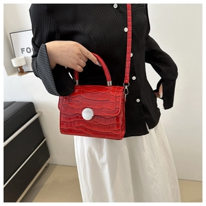 Détail d'un sac bandoulière rouge texture crocodile avec boucle argentée sur mannequin