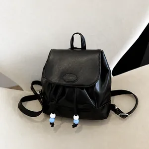 Detalle de una mini mochila de cuero negro con logo Fashion y cordón con cuentas