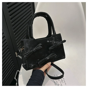 Détail d'un sac à main noir en similicuir avec texture vintage et nœuds élégants