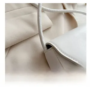 Close-up of white leather handbag showing meticulous stitching and cylinder shoulder strap