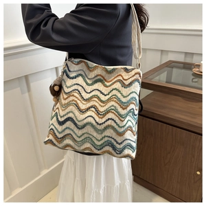 Detail of colorful wavy embroidered texture on a woven tote bag with a plush pom-pom