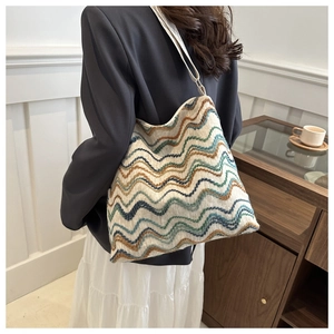 Detail of bohemian knitted tote bag with colorful wave patterns and white rope strap