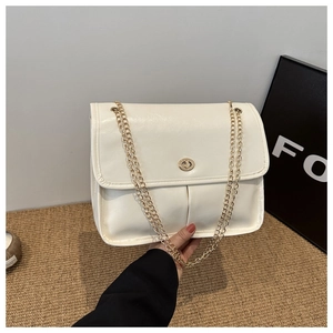 Detail of cream white chain bag with golden swivel lock and pleated faux leather