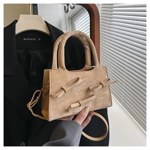 Détail du sac à main en cuir beige abricot avec trois nœuds décoratifs élégants