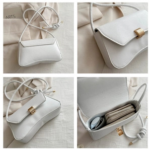 Detail view of cream white underarm bag with wavy base design and gold metal buckle