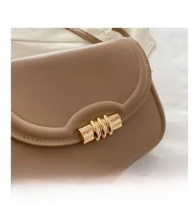 Gros plan du sac en cuir camel avec bord festonné et boucle métallique dorée chic
