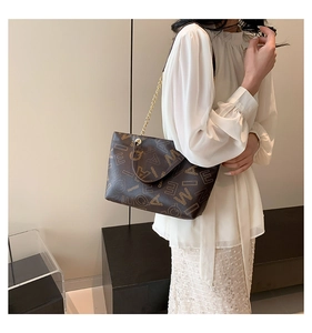 Close-up of brown tote bag featuring letter prints and elegant metal chain strap