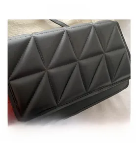 Detail der schwarzen Umhängetasche mit geometrischer Dreieckssteppung und mattem Leder