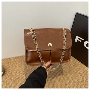 Detail of vintage brown shoulder bag with golden round swivel lock and chain strap