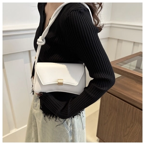 Close-up of white leather shoulder bag featuring gold buckle and knotted strap detail