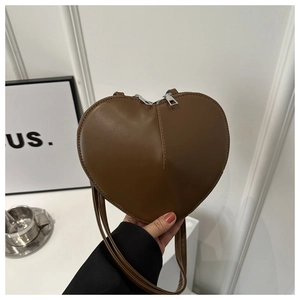 Détail d'un sac bandoulière marron foncé en forme de cœur avec double fermeture éclair
