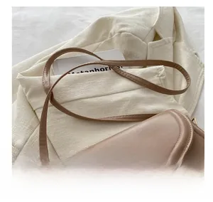 Détail d'un sac bandoulière marron en PU avec fermoir doré ondulé et bandoulière réglable