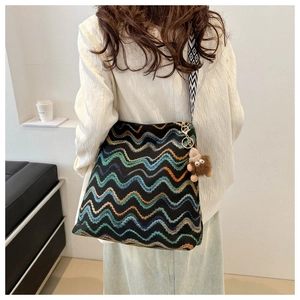 Detail of bohemian knit bucket bag with wave patterns and a wide jacquard strap