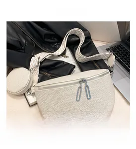 Close-up of white pebble leather saddle bag with wide geometric woven shoulder strap