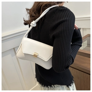 Close-up of white PU leather bag with curved base and golden metal magnetic buckle detail