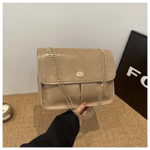 Detailed view of khaki chain bag with golden rotating lock and glossy leather texture